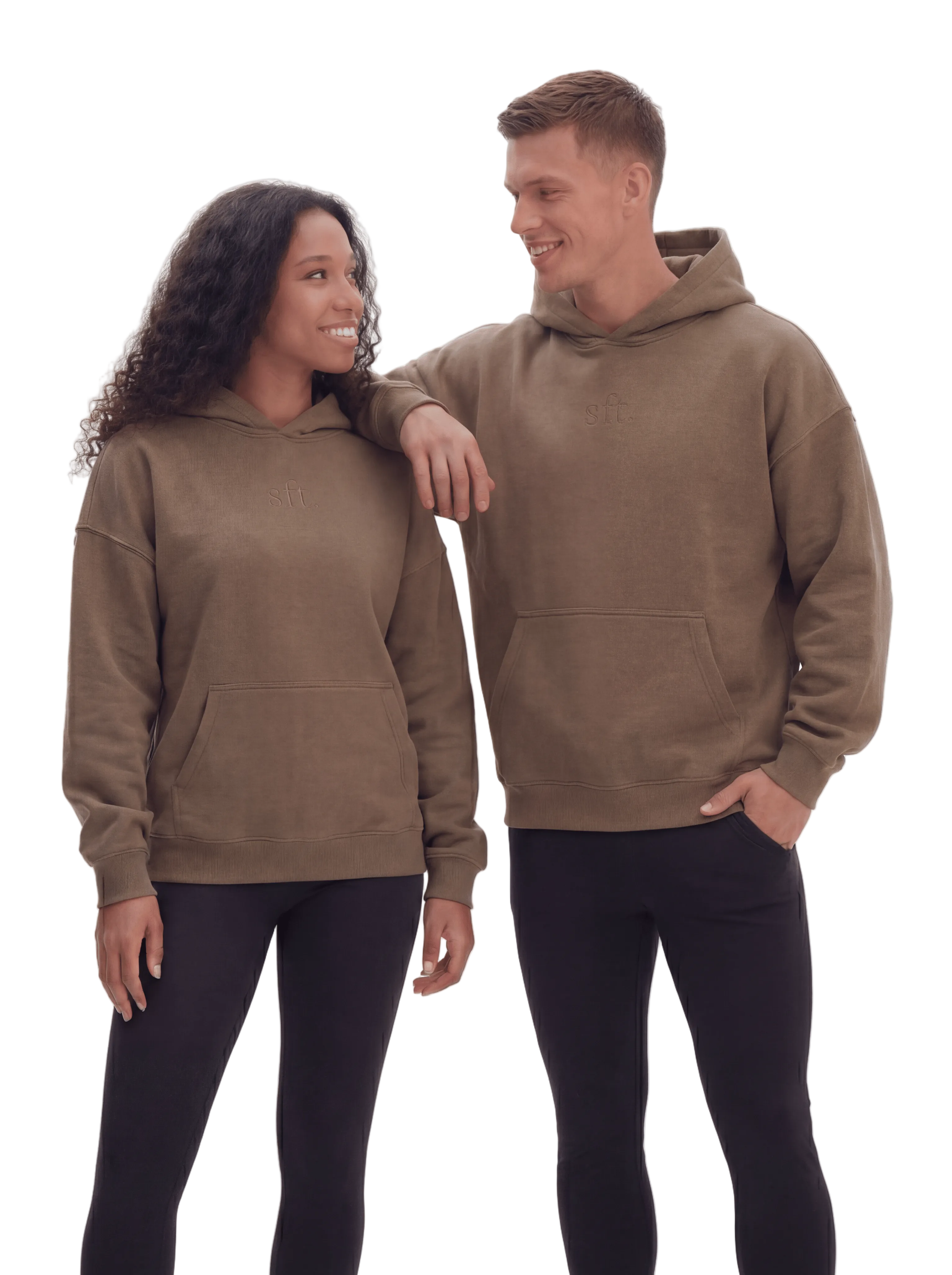 Two people wearing matching brown hoodies and black leggings on a white background