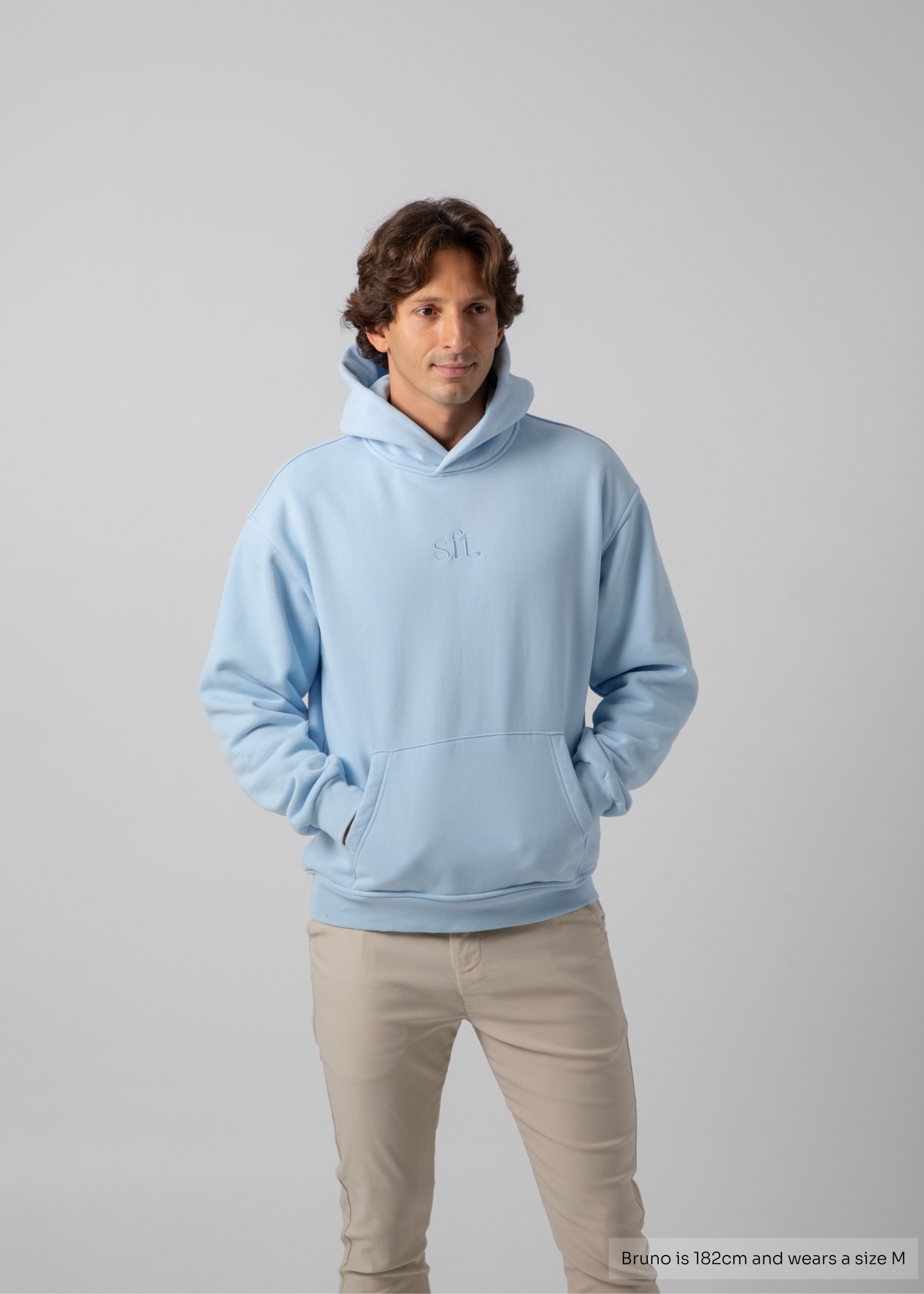 Man wearing a light blue hoodie on a gray background