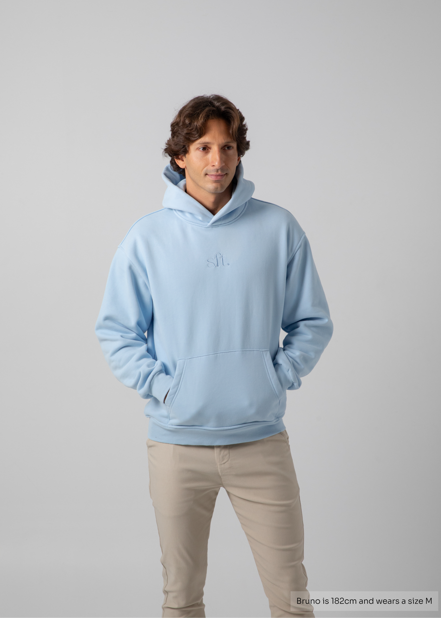 Man wearing a light blue hoodie on a gray background